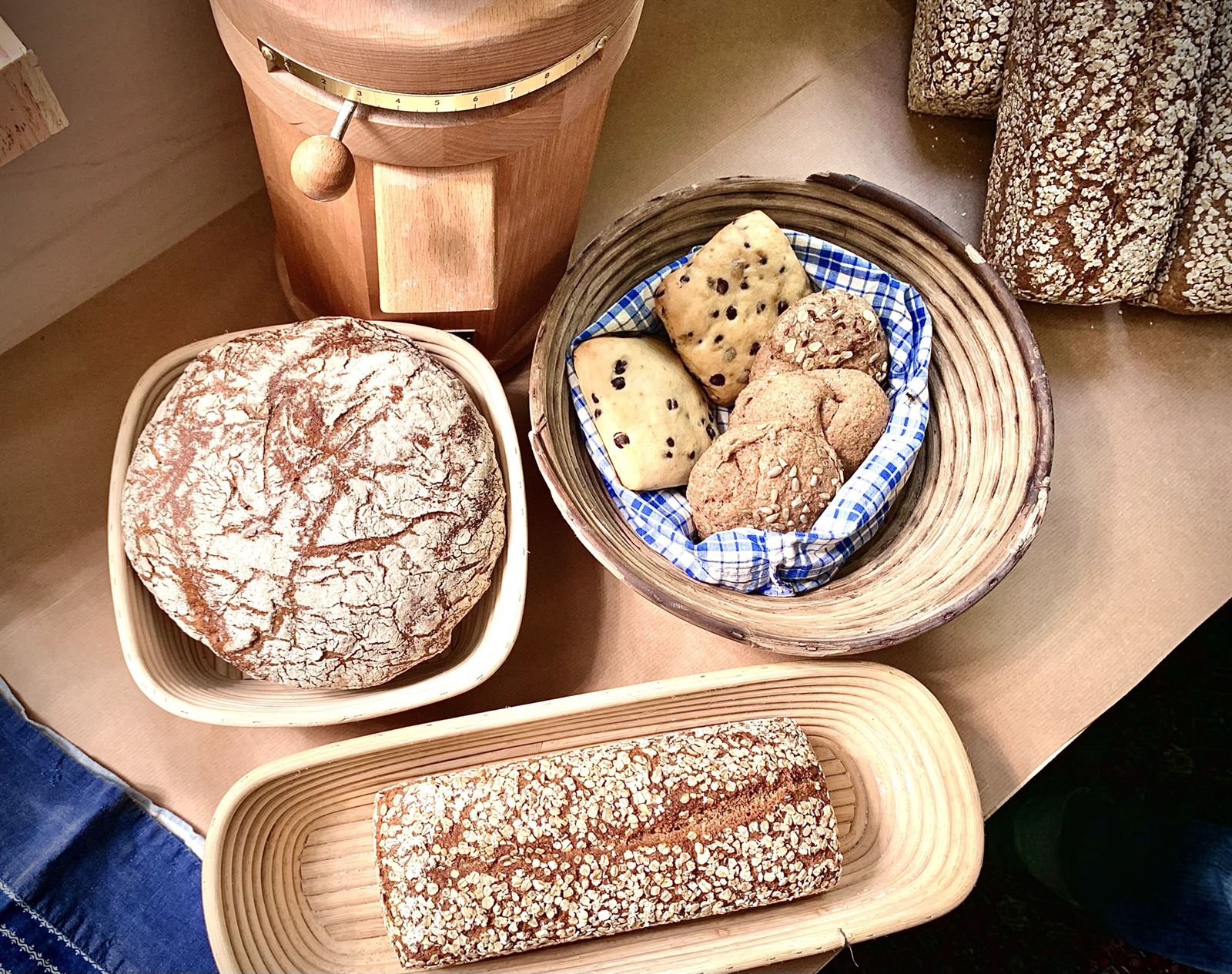Ein Wochenanteil: Brote und Brötchen in Gärkörben neben einer Getreidemühle
